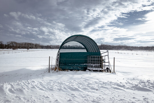 Winter auf dem Lande, eingeschneiter Plastik - Unterstand f&uuml;r Pferde in wei&szlig;er Winterlandschaft.