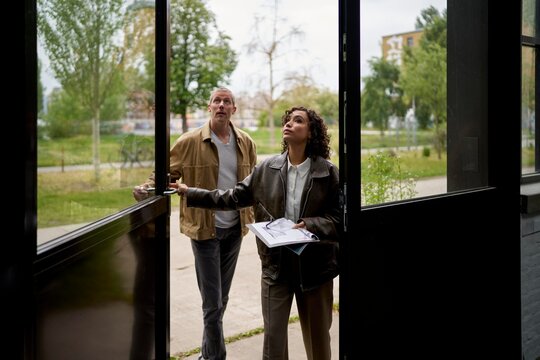 Couple Examines an Open Door in a Modern Urban Setting