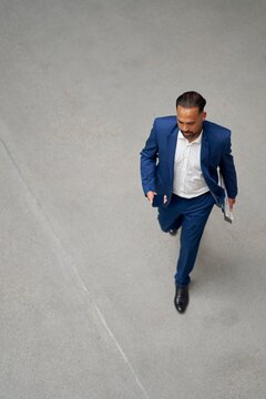 Businessman in Blue Suit Walking Confidently Indoors