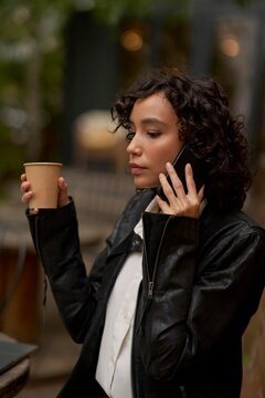 Woman Enjoying Coffee While Talking on the Phone in a Cozy Cafe