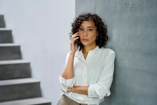 Woman talking on the phone while leaning against a wall