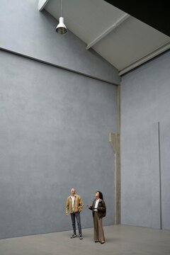 Couple in a vast loft with gray walls and high ceilings