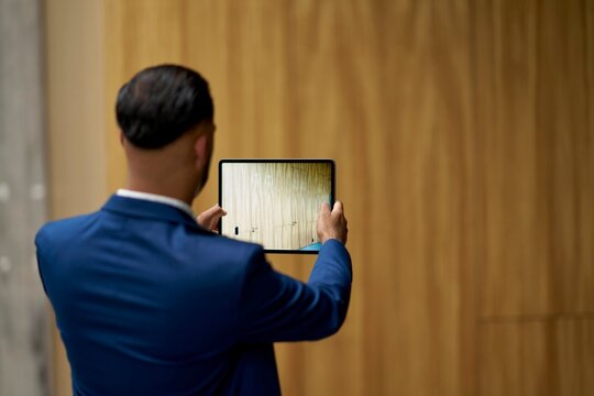 Man in Suit Captures Photo With Tablet in Modern Interior Space