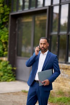 Businessman in a Suit Making a Phone Call Outside a Modern Building