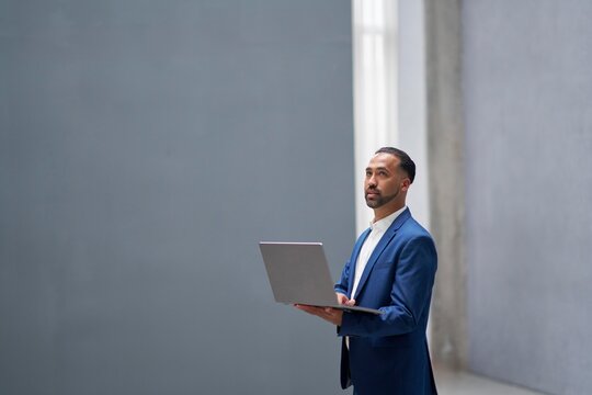 Businessman in blue suit working on laptop indoors