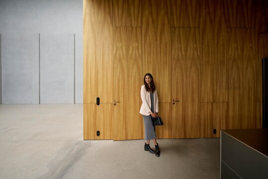 Stylish woman posing in modern interior space with wood accents