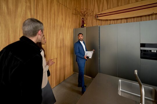 Real estate agent showcases modern kitchen to prospective buyers