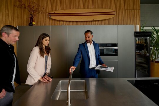 Two clients engage with a real estate agent in a modern kitchen space