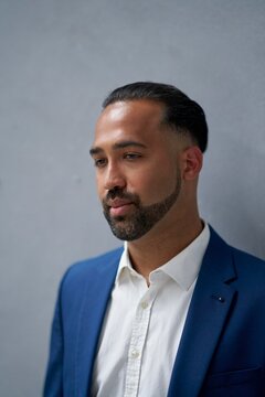 Man in a Blue Suit Poses Confidently by a Gray Wall