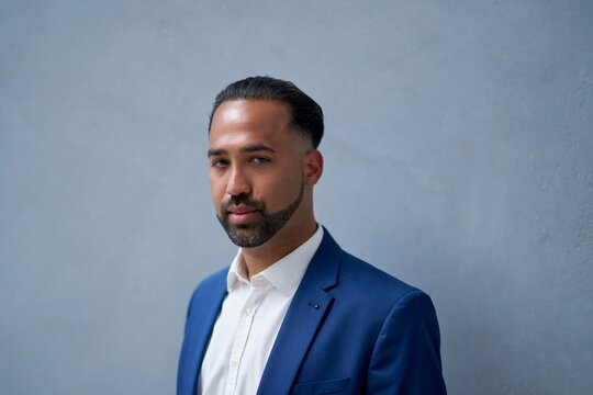 Confident Man in Blue Suit Poses Against a Textured Wall