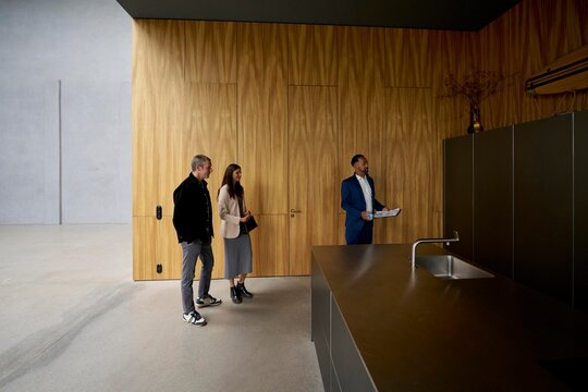 Real estate agent shows modern kitchen to potential buyers