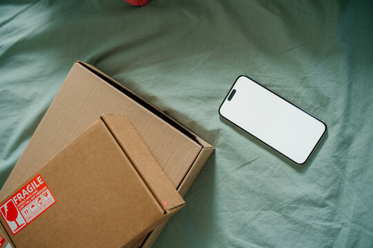 A mobile phone with white screen next to the parcels