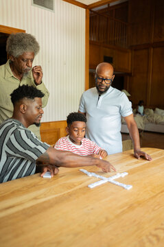 Family enjoying a game of dominoes at the kitchen table 