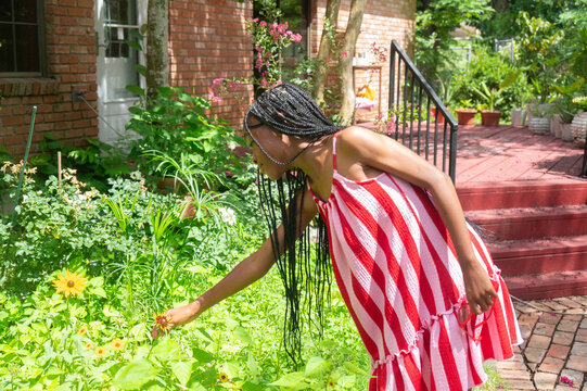 Girl in stripe dress smelling flowers from her garden