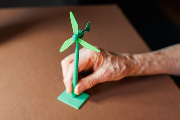 Model wind turbine is held by a hand on a flat surface in a workshop