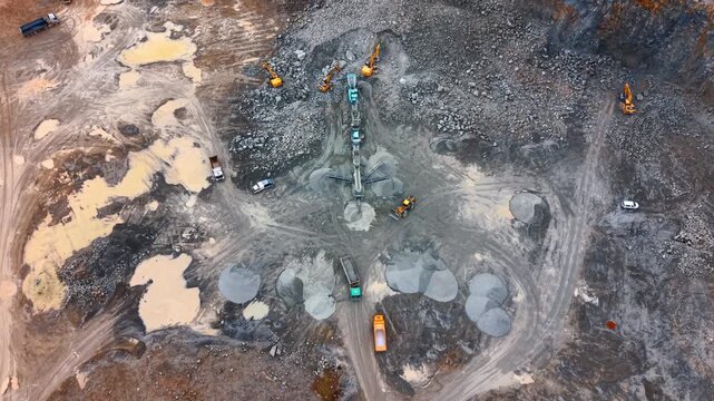 Aerial view of stone crushing plant and heavy machinery. Top down perspective of a mobile crushing facility surrounded by excavators and dump trucks.