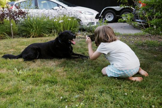 little kid taking portraits of her happy pet dog outside