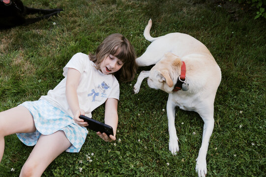 girl outside in yard taking selfie with her cute mutt dog