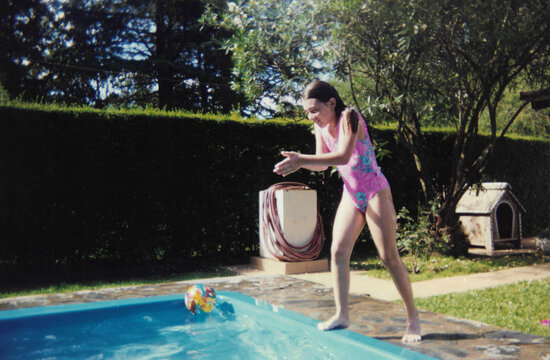 1990s analog photo of a girl about to jump into a pool on a summer day