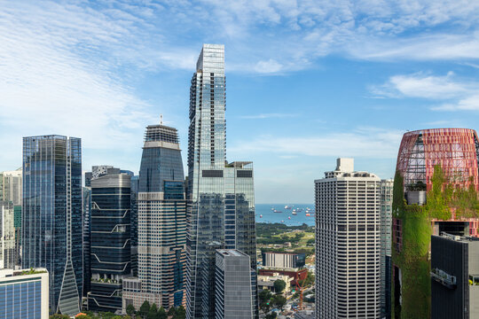 Modern glass skyscrapers of the Marina Bay financial district with sea and anchored ships visible in the background, Singapore
