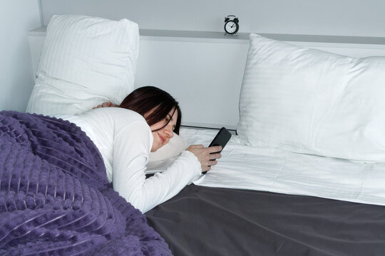 Woman in Bed Using a Mobile Phone. 