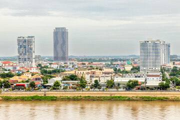 Obraz premium Modern apartment buildings rising above traditional houses along Tonle Sap riverbank in Phnom Penh, Cambodia