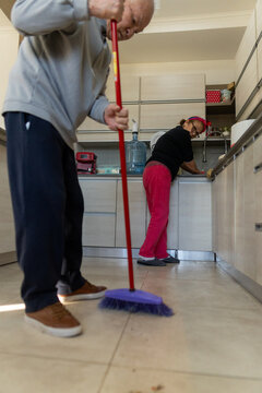 Elderly Couple Cleaning the Kitchen Floor Together in Bright Home