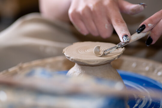 Faceless person making pot on potter's wheel in workshop