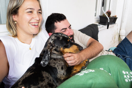 Couple relaxing on sofa with their dachshund dog enjoying weekend