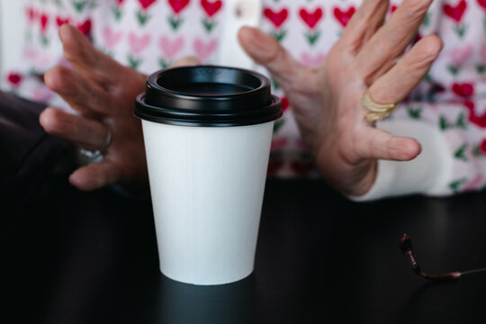 senior woman reaching for takeaway coffee