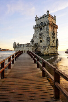 Iconic Bel&eacute;m Tower (Torre de Bel&eacute;m) at golden sunset, historic Manueline fortress on the Tagus River shore with wooden walkway, UNESCO World Heritage Site in Lisbon, Portugal, scenic evening light. 