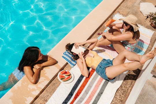 Summer moment of three friends relaxing at the swimming pool