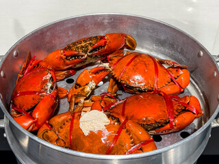 Selective focus of steamed orange in aluminum steamer tied with red string, Scylla serrata is an ecologically important species of crab found in the estuaries and mangroves, Prepare seafood meal diner