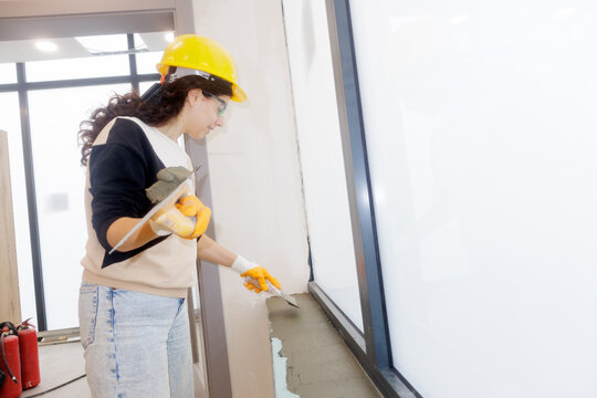 A young woman applies tile adhesive