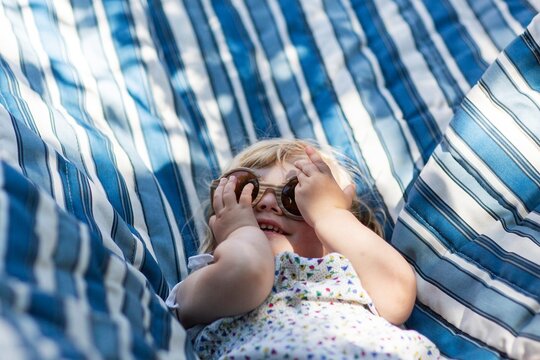 Happy toddler relaxing in hammock with sunglasses

