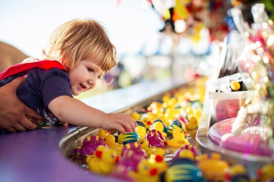 Toddler plays duck game at carnival
