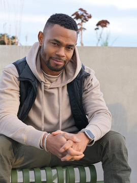Man Sitting Outdoors in Casual Attire During Late Afternoon