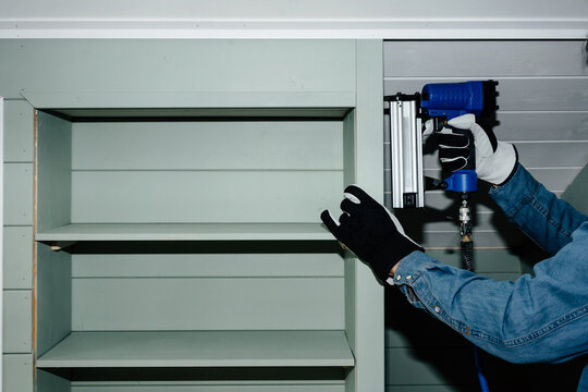 Man fixing wooden corner with pneumatic nail gun