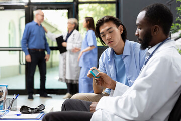 African american doctor measures blood sugar levels with precision during clinic visit. Asian man...