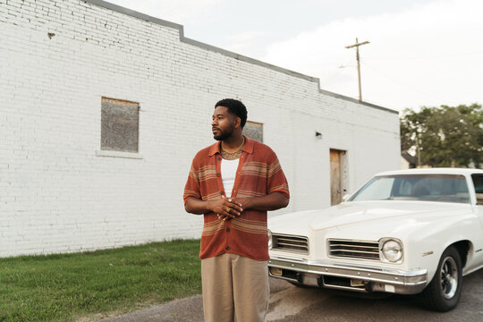 Young Stylish Man Posing With Vintage Car By A White Brick Wall