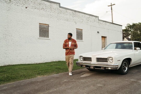 Young Stylish Man Posing With Vintage Car By A White Brick Wall