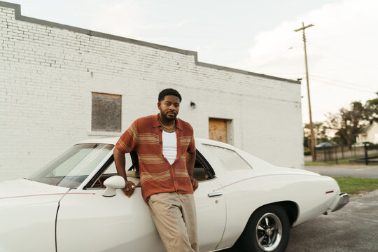 Young Stylish Man Posing With Vintage Car By A White Brick Wall
