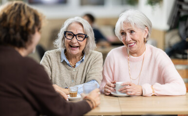 Large family is having breakfast in a cozy cafe, discussing the news.
