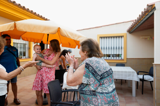 Grandmother claps for baby in patio