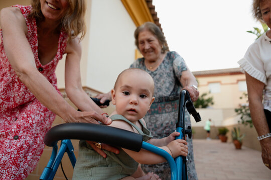 Baby riding a walker outdoors with family