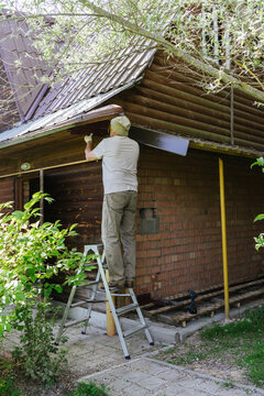 A man repairs the roof of a wooden house