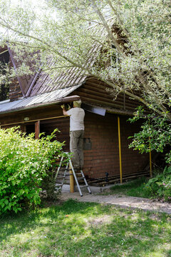 A man repairs the roof of a wooden house