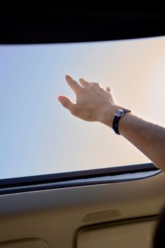 Reaching for the Sky From a Car Sunroof on a Sunny Day