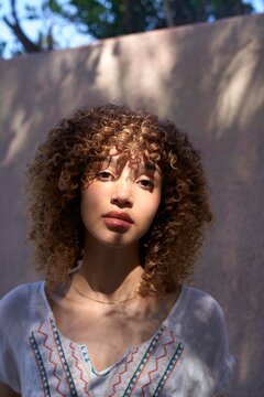 Curly haired woman standing in soft sunlight outdoors