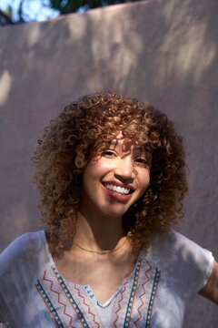 Smiling Woman With Curly Hair Posed Outdoors in Natural Light